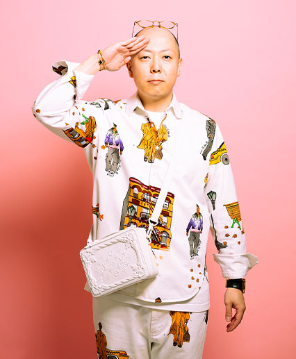 Chef Masaki Saito saluting against a pink background